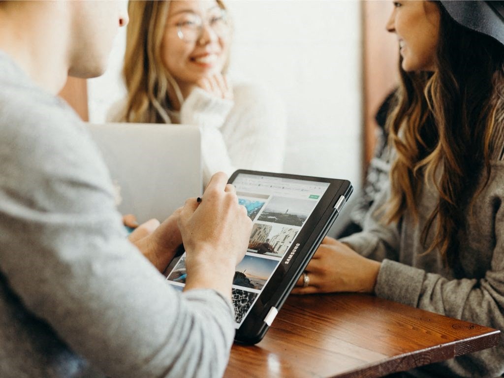 One male two females at a table looking at a tablet