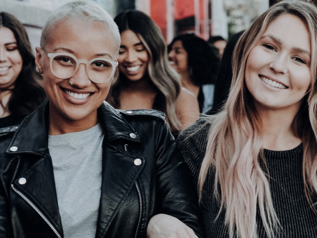 A large group of women walk down a city sidewalk together.