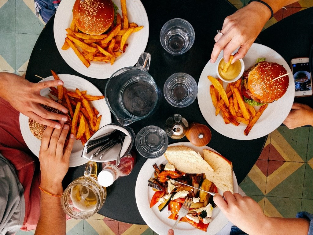 An aerial view of four friends eating lunch at a restaurant table.