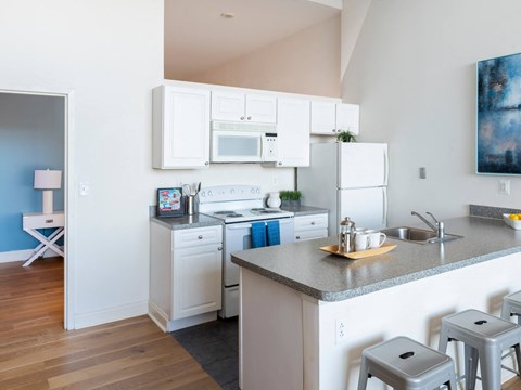 a kitchen with white appliances and a counter with stools
