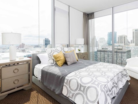 A bedroom with a large bed and a city view.