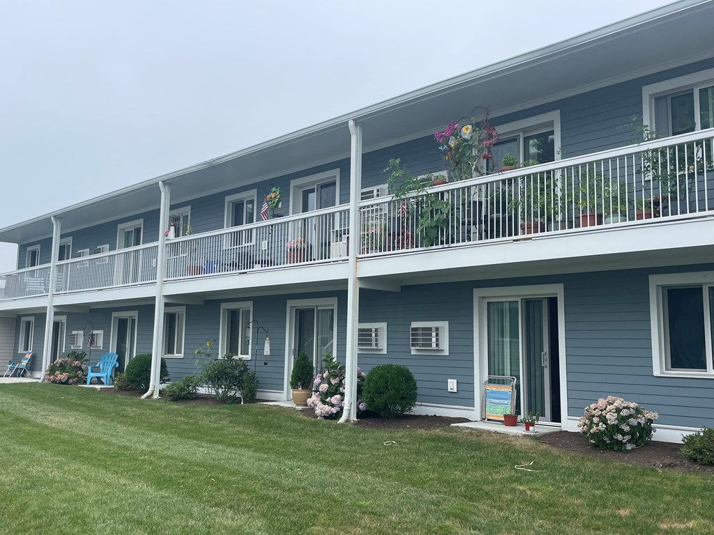 a blue building with a balcony and a grass field