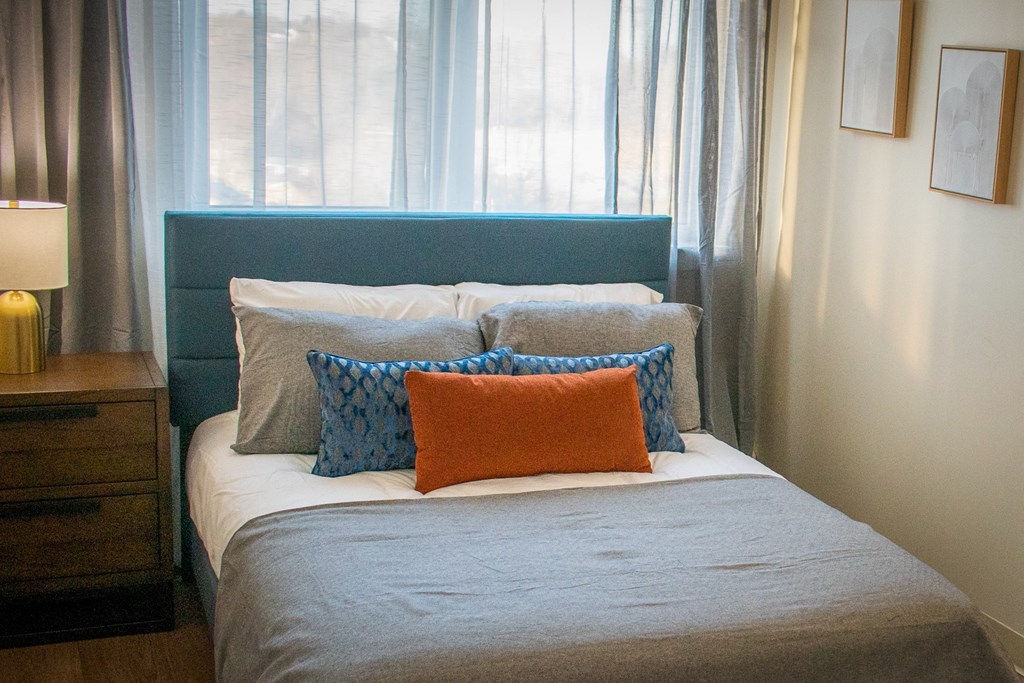 a bed with pillows in a room with a window