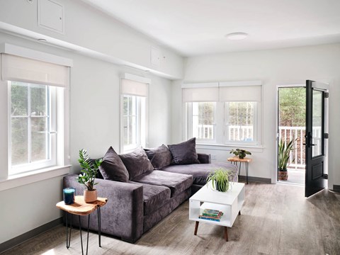 A living room with a grey couch, a white coffee table, and a small wooden side table.
