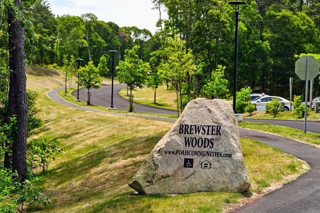 a large rock with the words brewery woods written on it in front of a road and trees