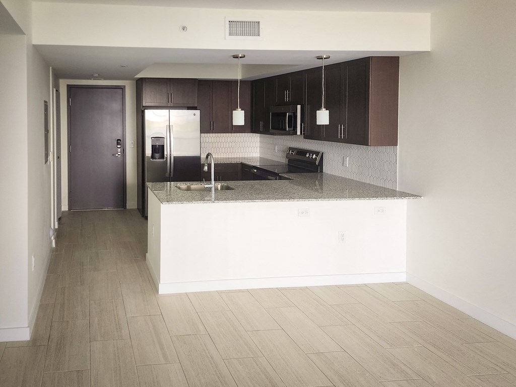 an empty kitchen with a counter top and a refrigerator