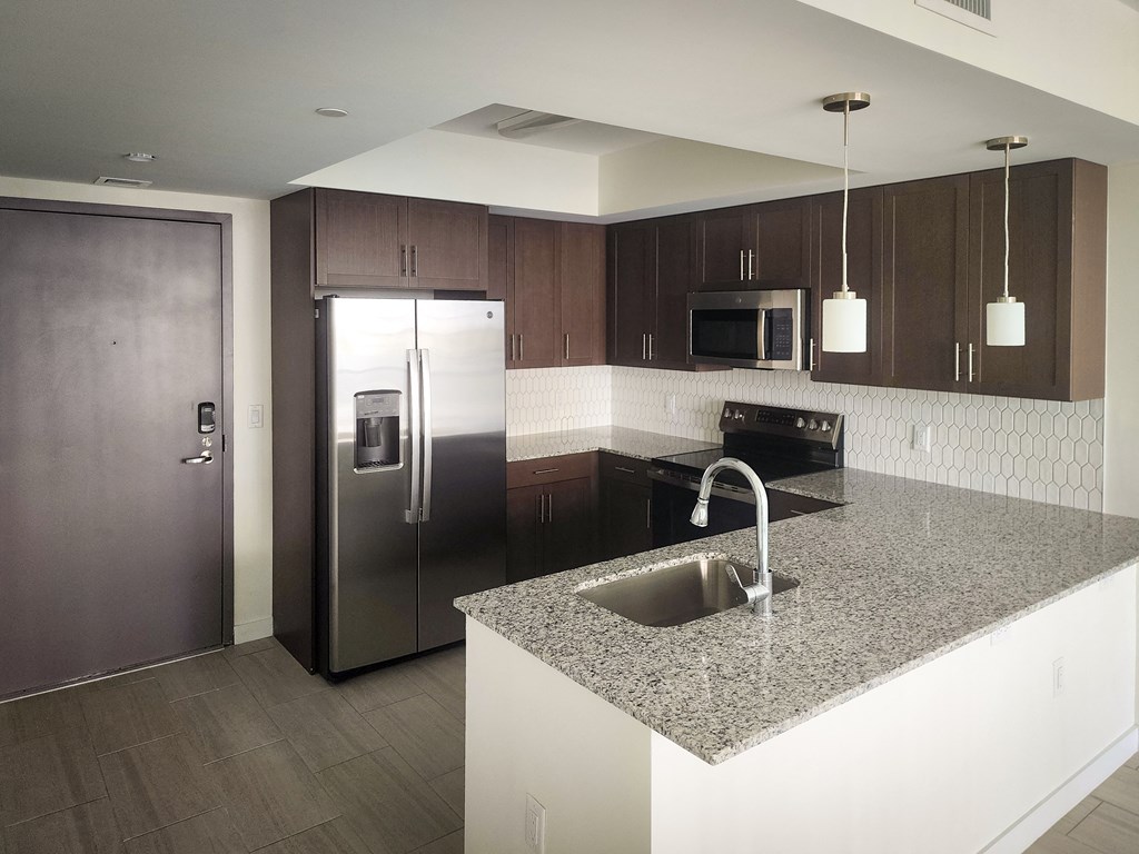 a kitchen with granite counter tops and a stainless steel refrigerator