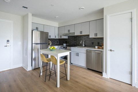 A kitchen with a table and chairs in front of a refrigerator.
