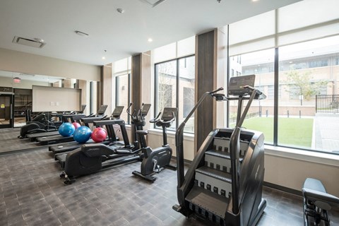 A gym with treadmills, elliptical machines, and a weight rack.