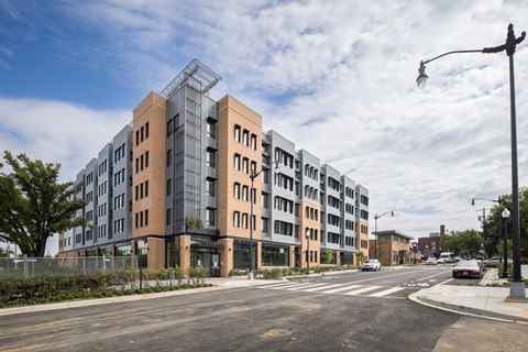 A modern apartment building with a glass entrance and a street in front.