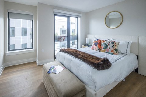 A bedroom with a large bed and a window overlooking a cityscape.