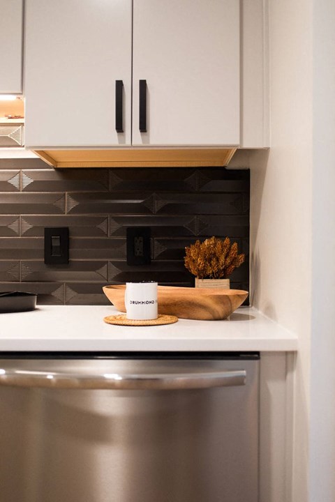 a small kitchen with white cabinets and a stainless steel refrigerator