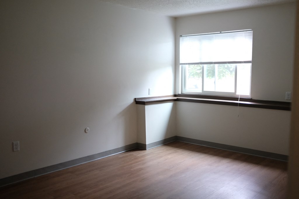 an empty room with a window and wooden floors