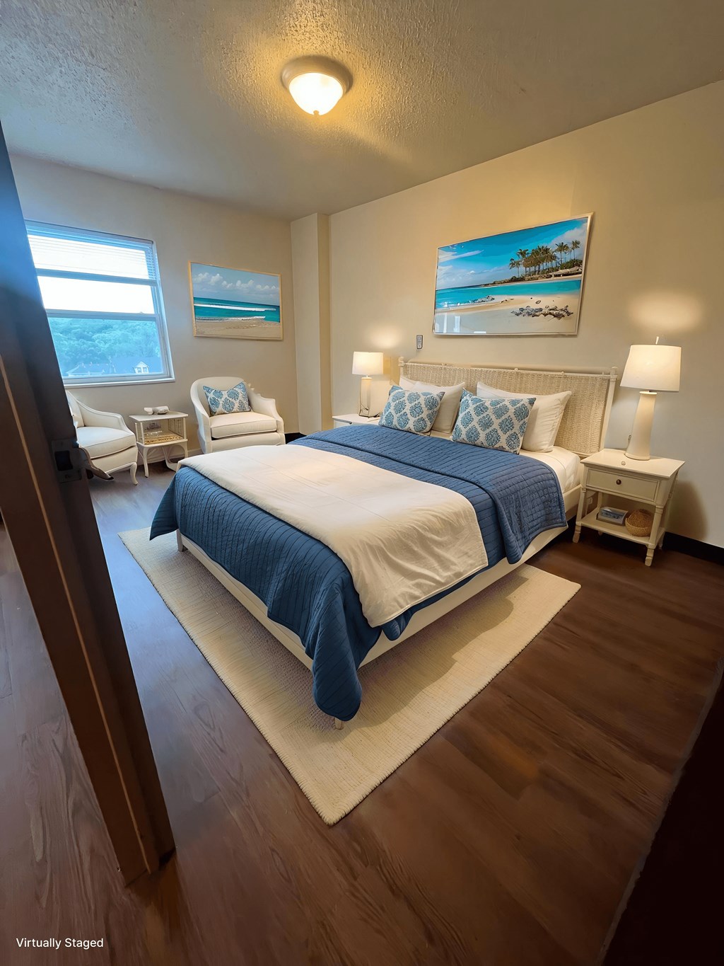 A bedroom with a bed, two chairs, and a painting on the wall.