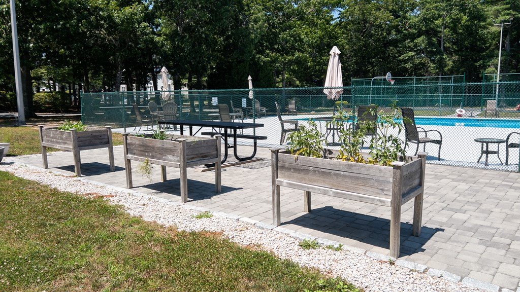 A wooden bench with a planter box on top is situated in a park.