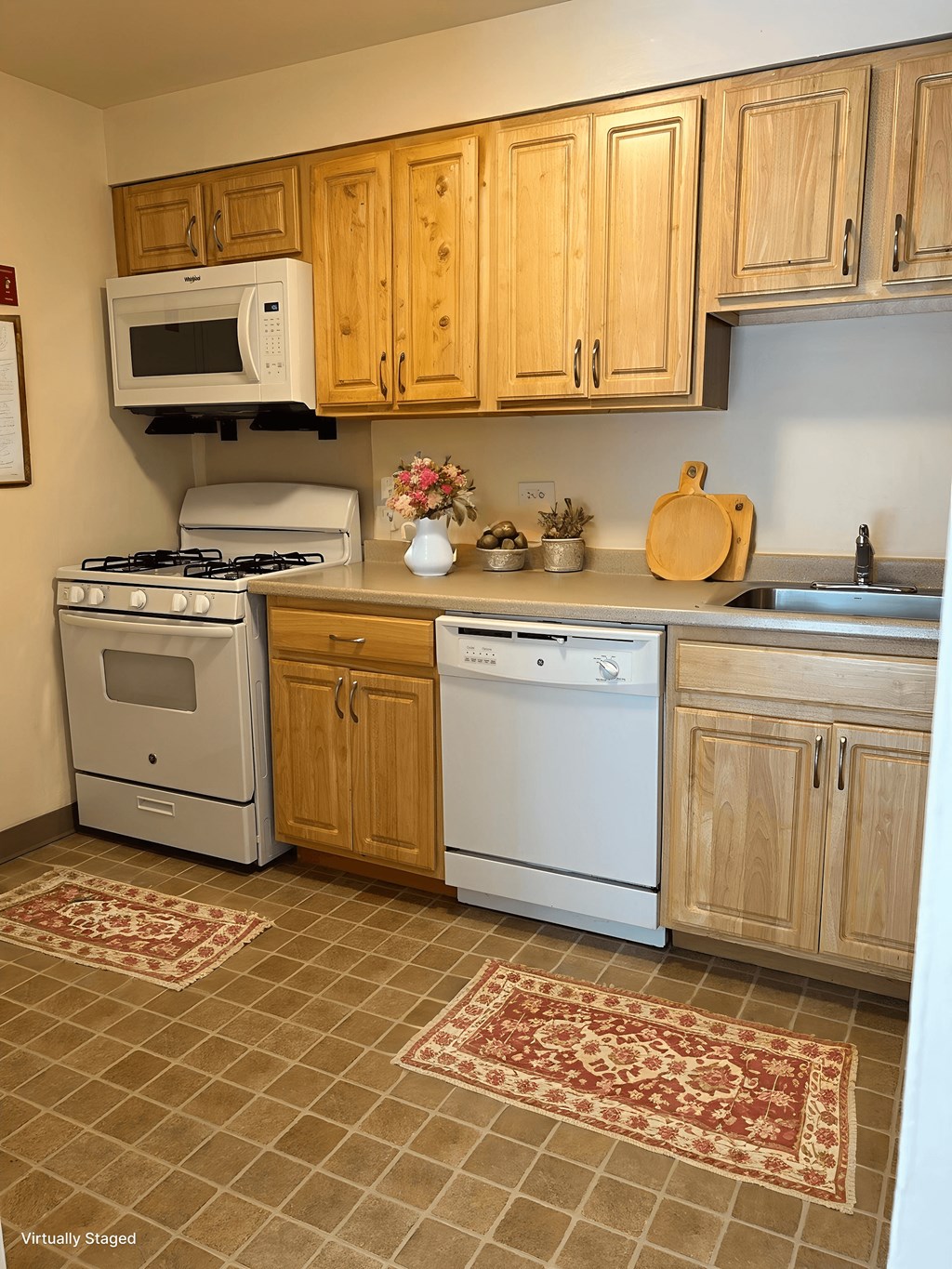 A kitchen with a white stove and oven, a microwave, and wooden cabinets.