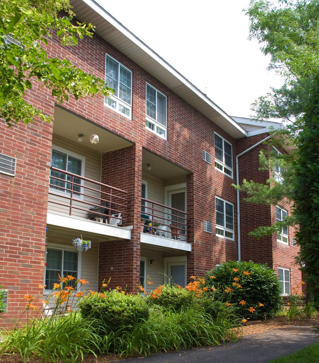 a red brick apartment building with balconies and flowers