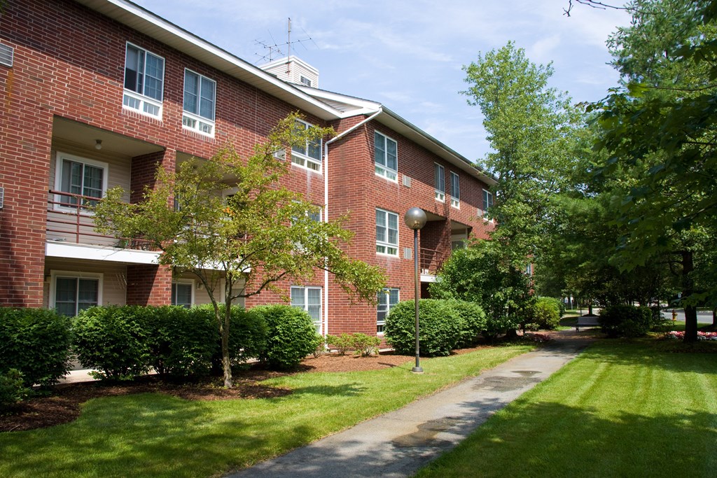 a brick apartment building with a sidewalk in front of it