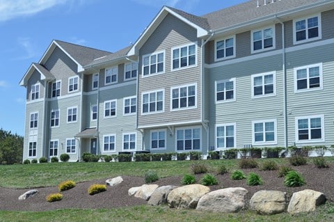 a large apartment building with large rocks in front of it