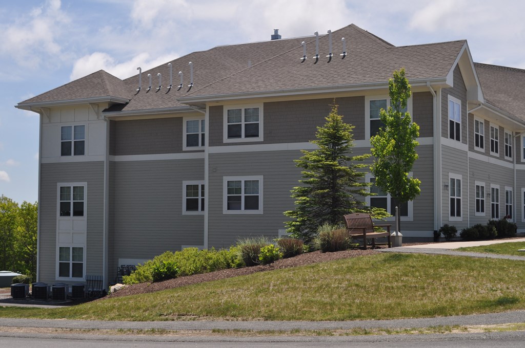 a large gray house with a bench in front of it