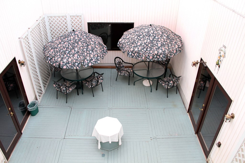 a patio with tables and umbrellas in a courtyard