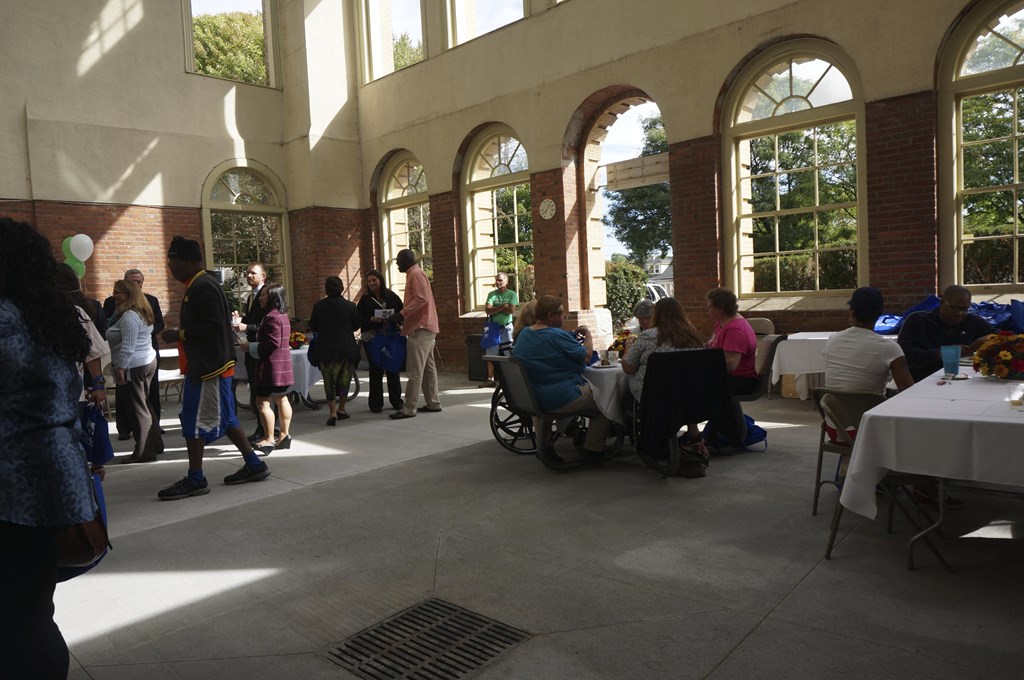 a crowd of people standing around tables in a building with large windows