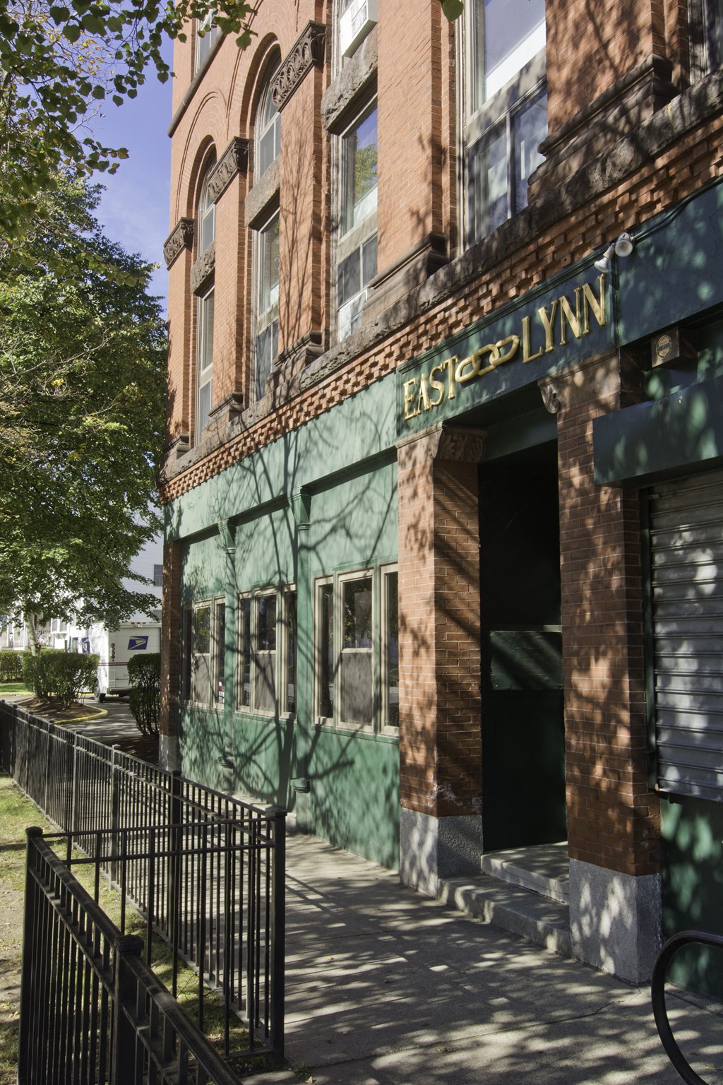 an old building with a green facade and a sidewalk