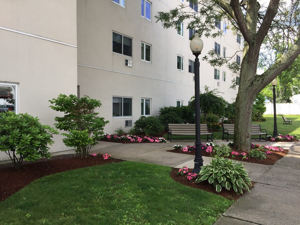 a courtyard with benches and trees in front of a building