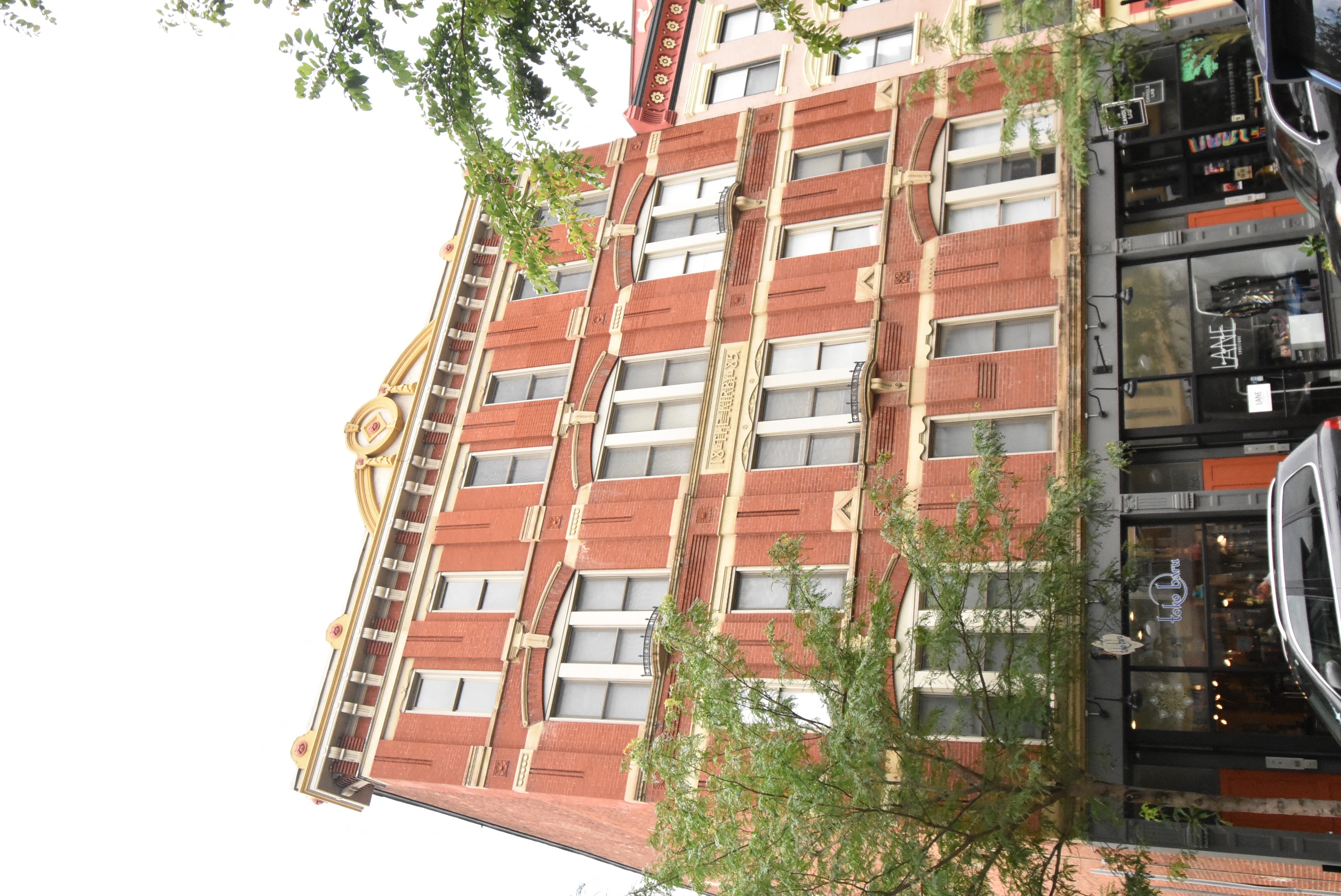 A tall building with a red brick facade and a yellow trim.