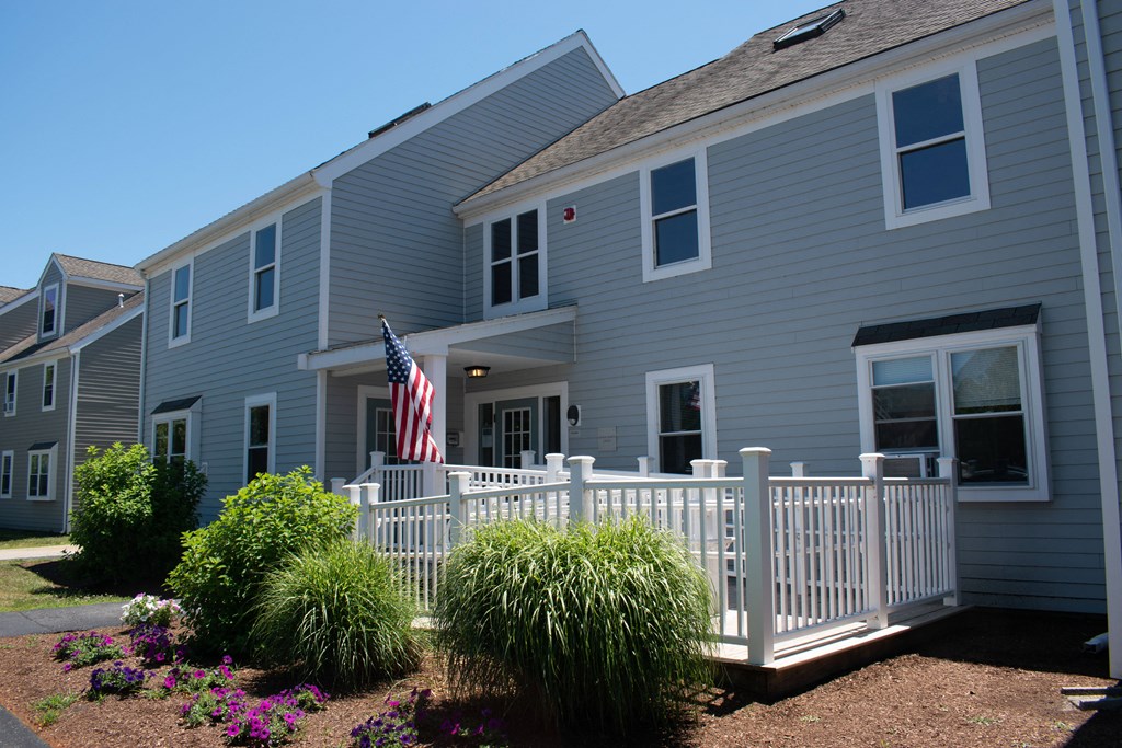 a blue house with a white fence and an flag
