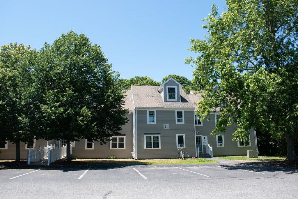 a large gray house with trees in a parking lot