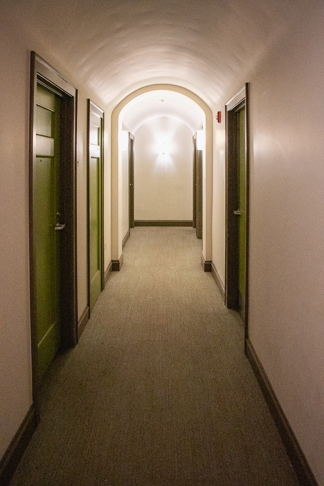 a long hallway with doors and a carpeted floor