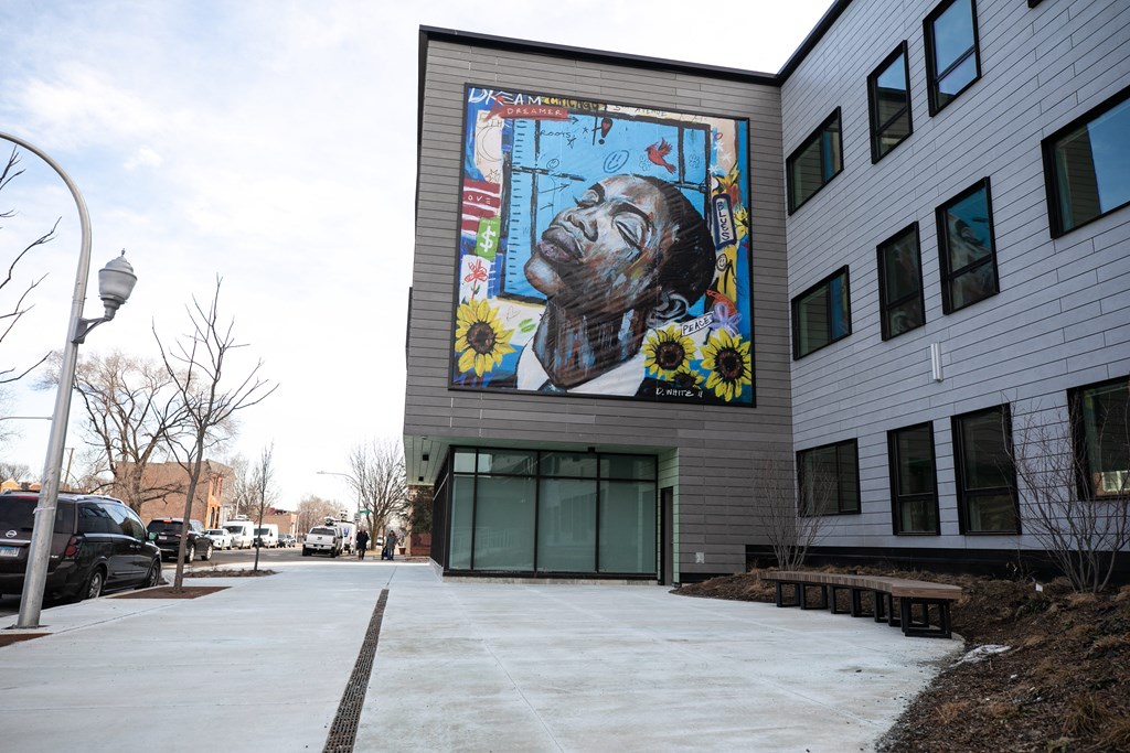 A mural of a man with flowers is on the side of a building.