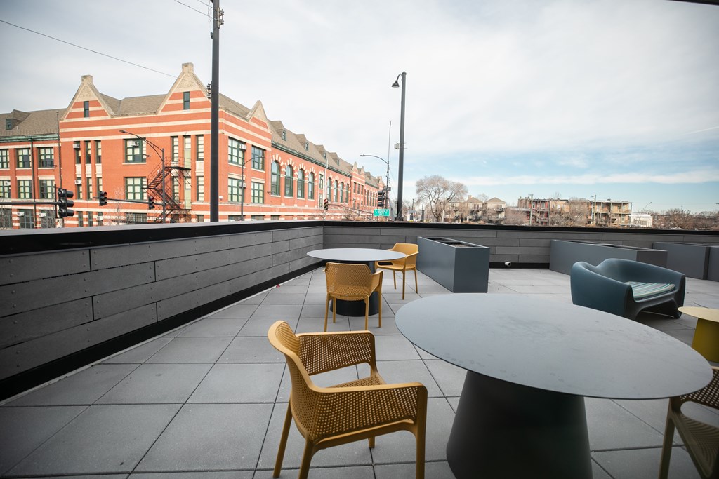 A patio with a table and chairs overlooking a brick building.