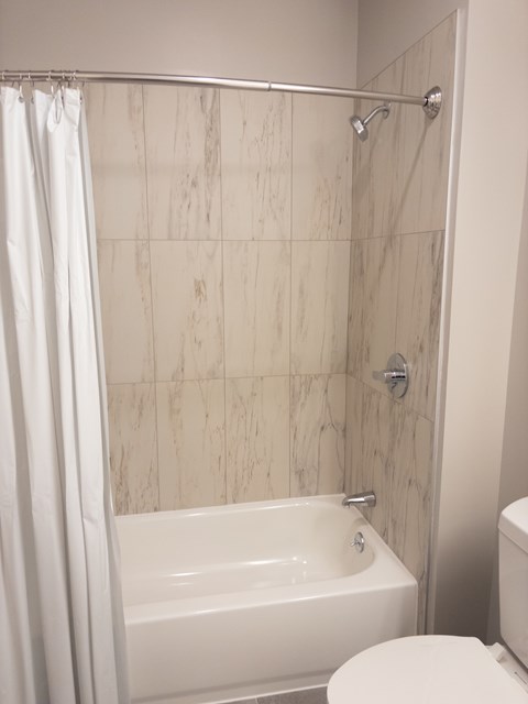 A white bathroom with a marble tile shower.