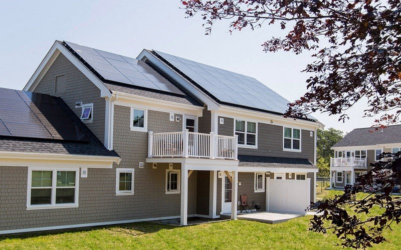 a gray house with solar panels on the roof