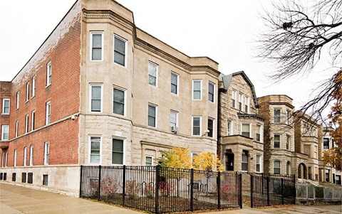 A large red brick building with a black fence in front.