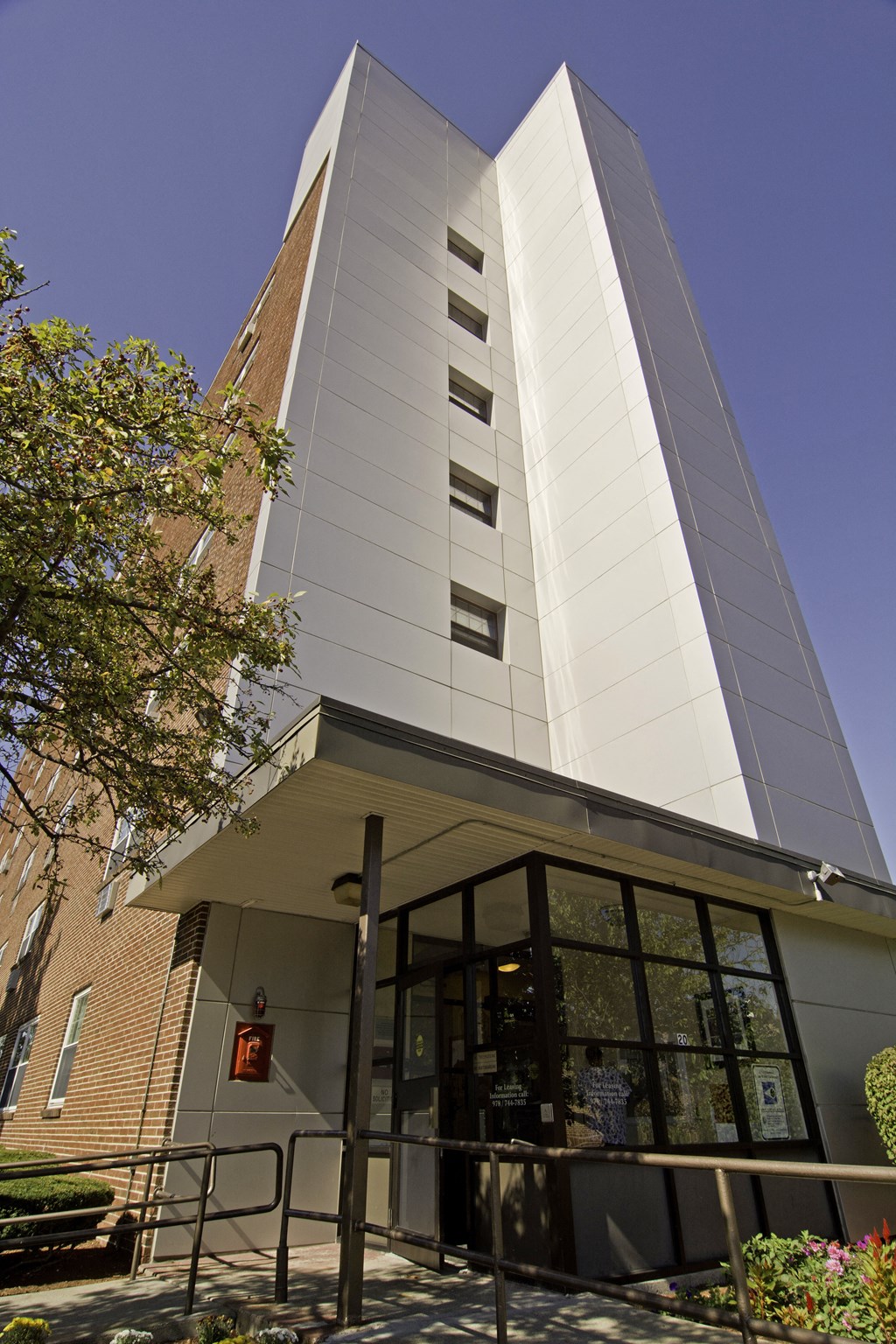 a tall white building with a glass entrance and a blue sky