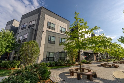 a courtyard with benches and trees in front of a building