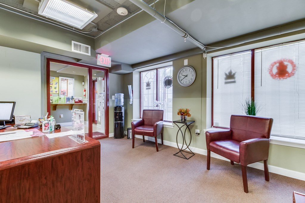 a lobby with two red chairs and a clock on the wall