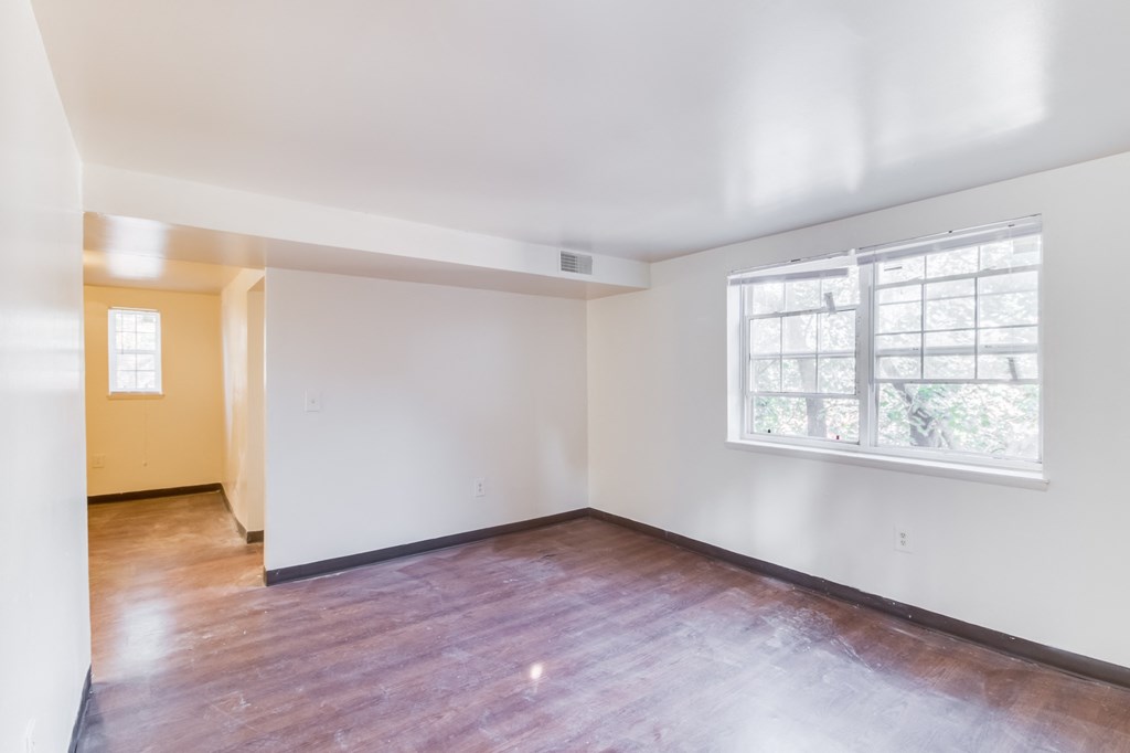 an empty living room with wood floors and a large window