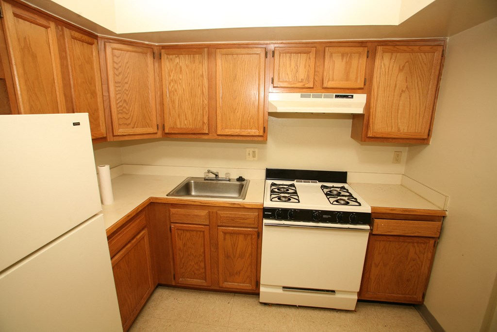 an empty kitchen with wooden cabinets and white appliances