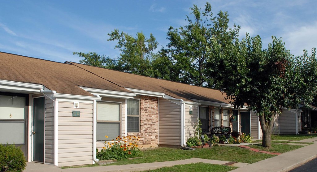 a small apartment building with a tree in front of it