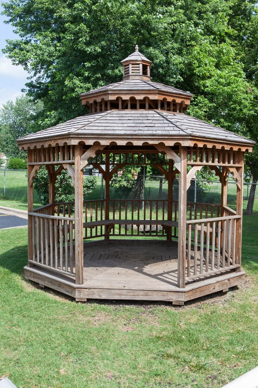 a gazebo with a bench in a park