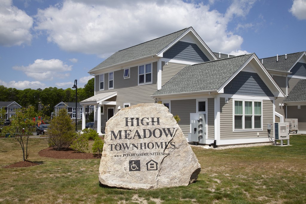 a large rock in front of a house with a sign for high meadow apartments