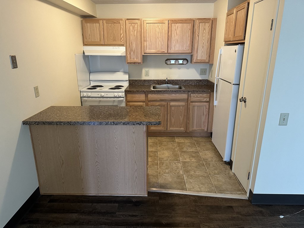 an empty kitchen with wooden cabinets and a white refrigerator