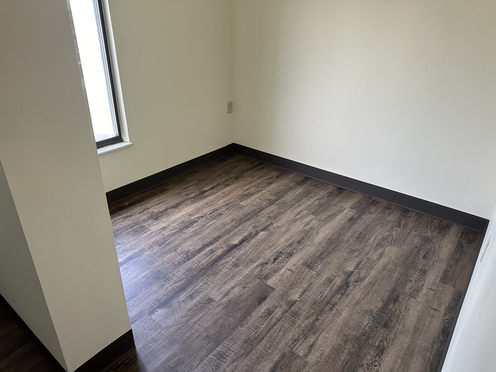 an empty room with wooden floors and a window