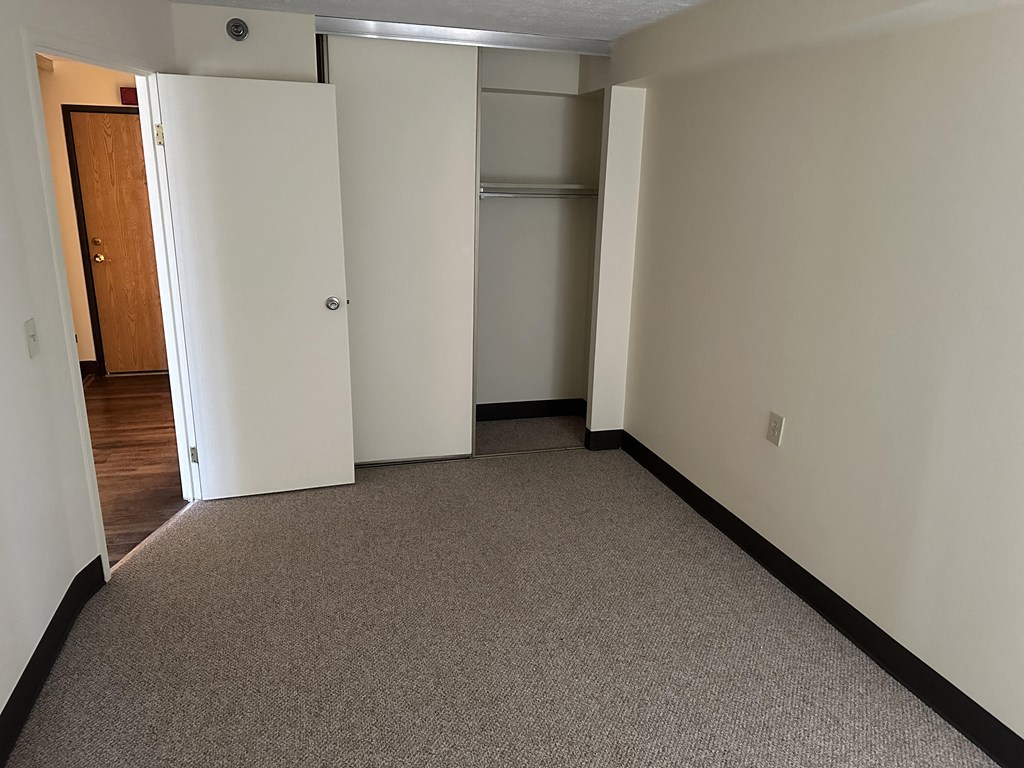 an empty carpeted bedroom with a closet