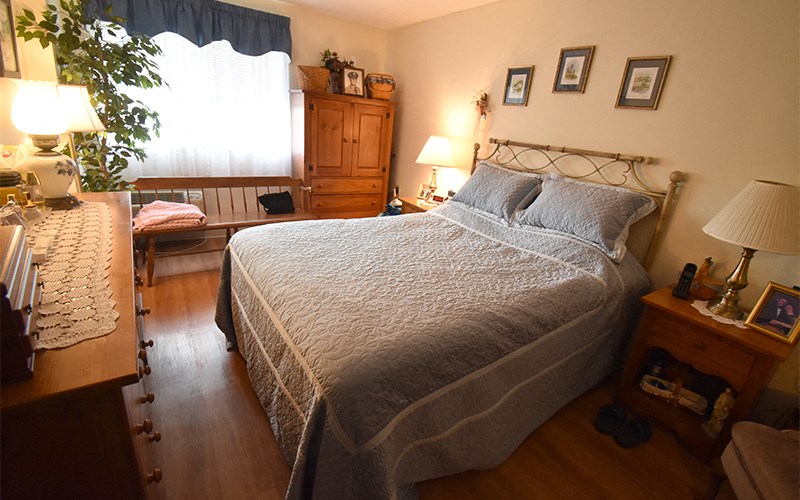 A bedroom with a bed, nightstand, and a window with curtains.