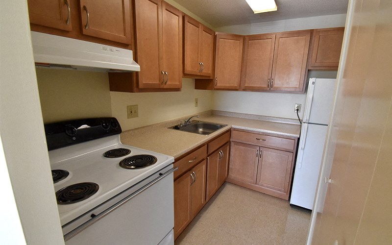 A kitchen with brown cabinets and white appliances.